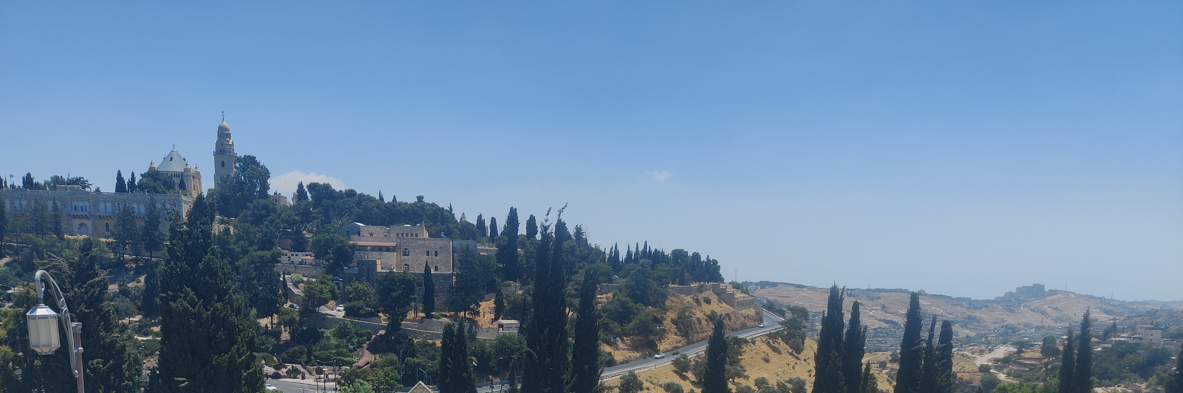 One of my favorite running places in Jerusalem. The image features lightly colored hills lined with thin trees with historic, brick buildings in the background.
